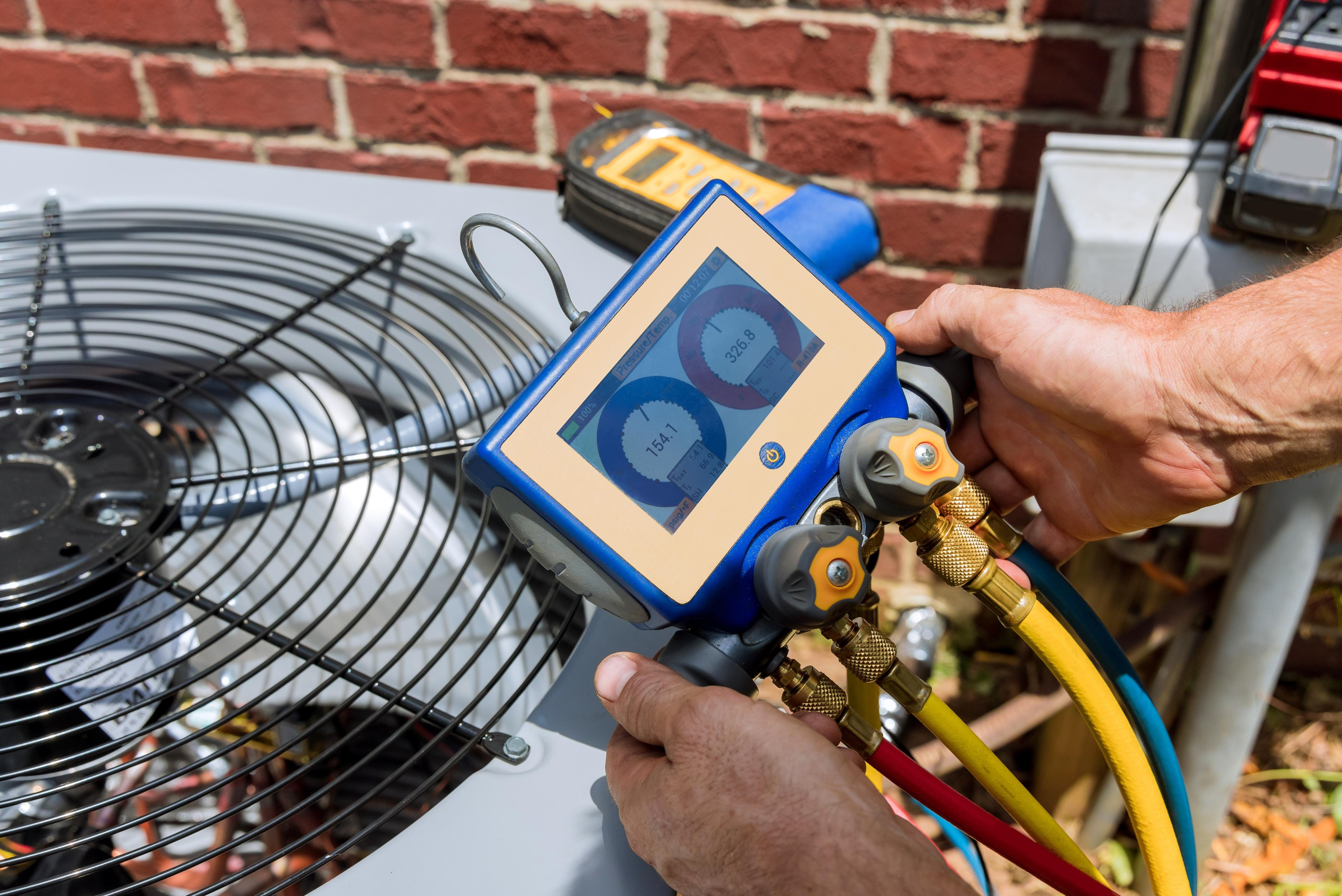 HVAC technician diagnosing an outdoor air conditioning unit